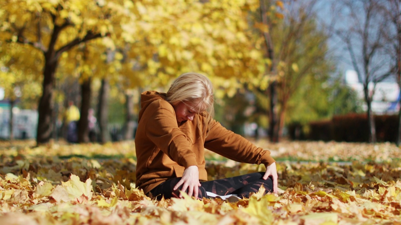 年轻的成年女子在秋季公园练习瑜伽视频素材