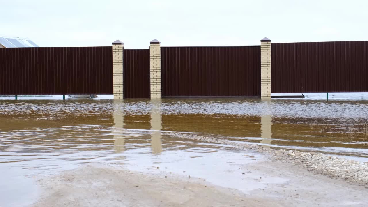 农村地区的春季洪水——河水泛滥，围墙后面的房屋被淹没。雪和大雨融化后的元素视频素材