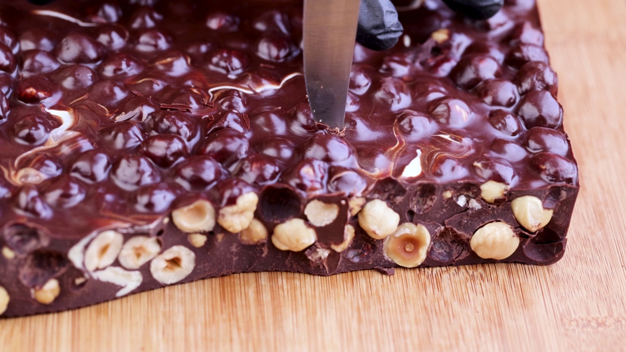 在木桌上把巧克力和榛子一起切成小块视频素材