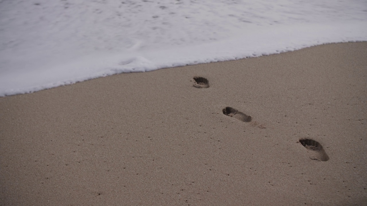 沙滩上的脚印被海浪冲走了视频下载