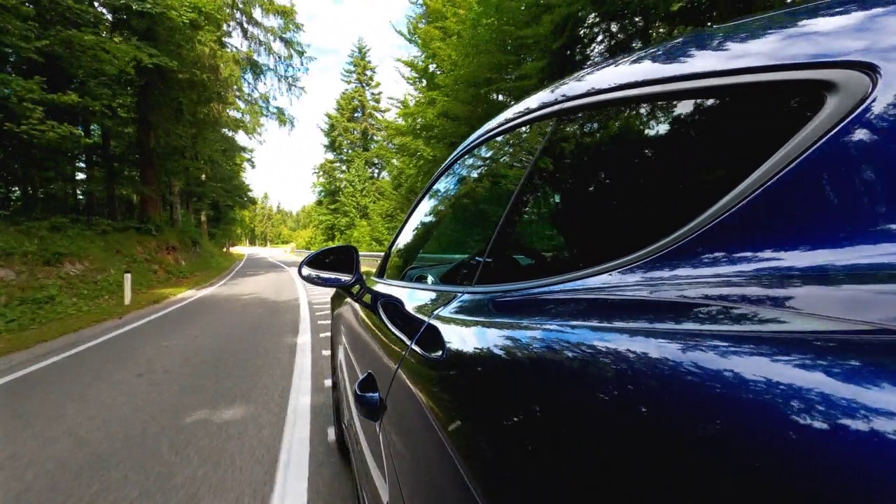 一辆跑车在蜿蜒的乡间小路上疾驰，四周绿树成荫视频素材