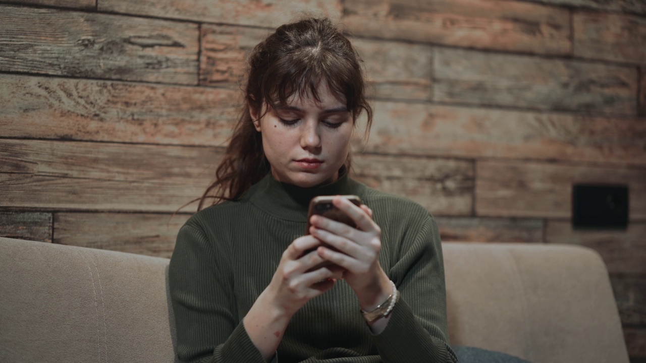 年轻伤心担心的女孩用手机发短信或在社交媒体上接收负面情绪视频素材
