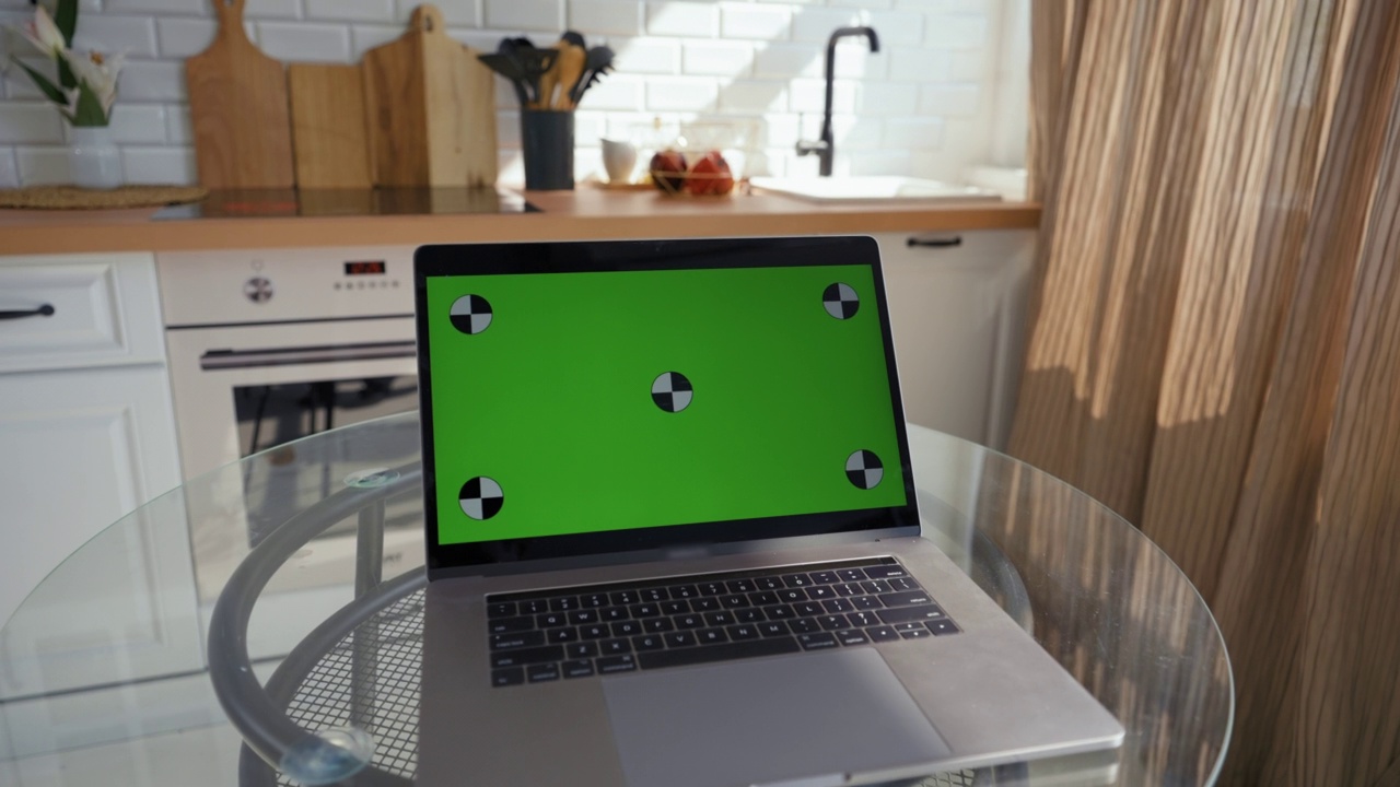 在玻璃桌面上打开绿色chromakey屏幕的笔记本电脑视频素材