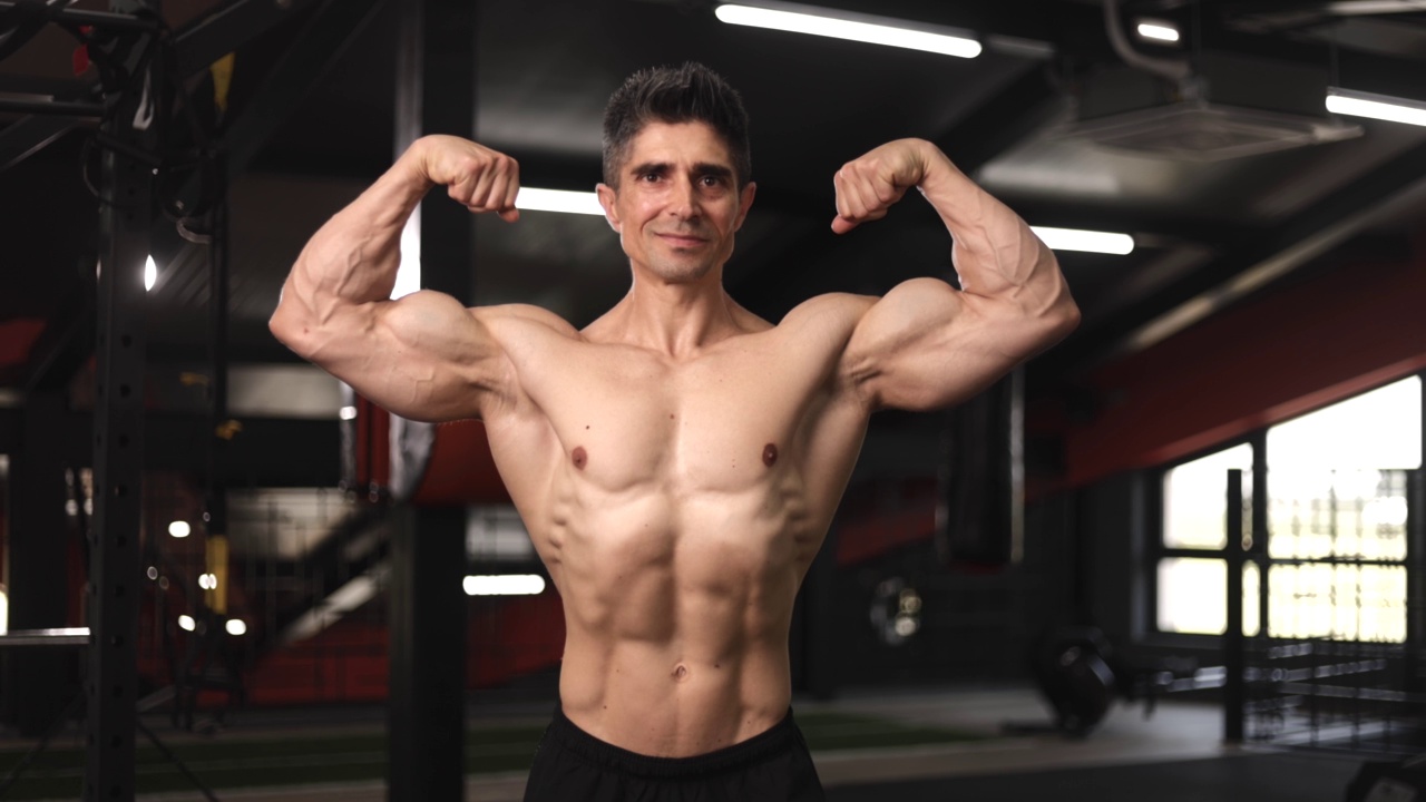 迷人的成熟男性健美运动员与完美的躯干摆出肌肉的身体在健身房视频素材