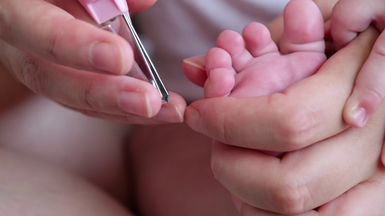 妈妈的手在修剪宝宝的脚指甲视频素材