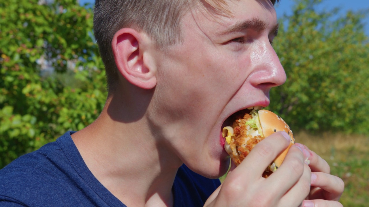 一个男人在城市公园里吃汉堡视频下载