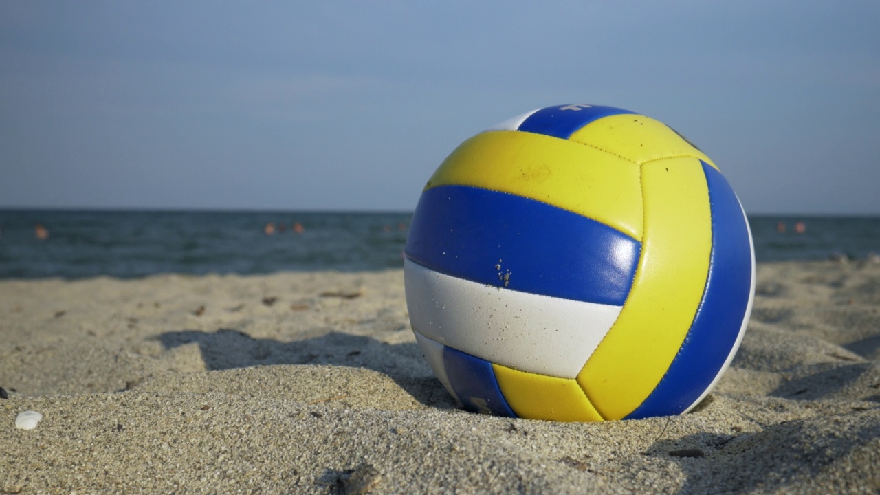 一个排球站在沙滩上的沙子上，在风中轻轻摇晃视频下载