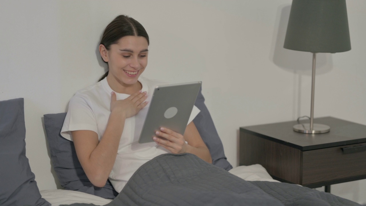 西班牙女性在床上用平板电脑视频通话视频素材