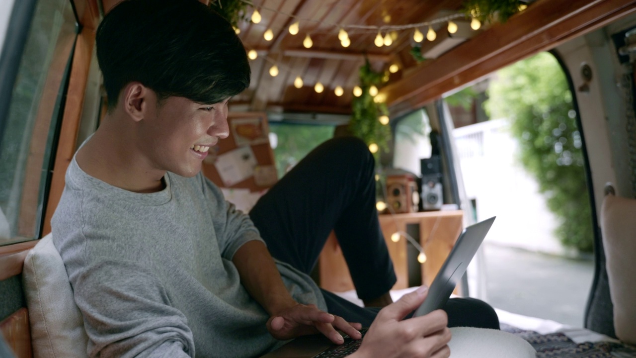 亚洲男性在露营车上使用电脑网上购物的场景，网上购物的概念视频下载