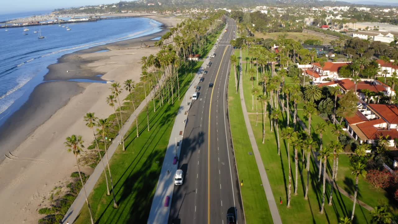 航拍前进的汽车移动在道路上的城市海滩在阳光明媚的日子-圣巴巴拉，加利福尼亚视频下载