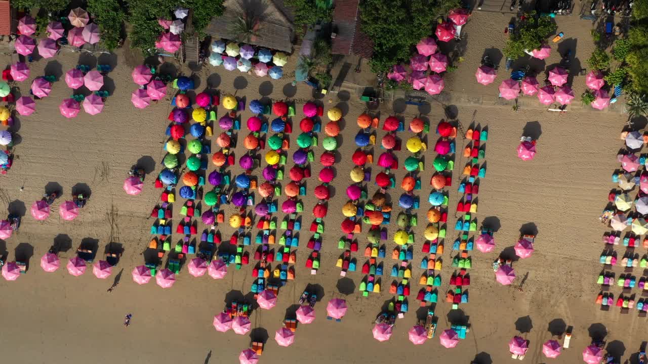 空中摇摄多色豆袋和阳伞在海滩，无人机在阳光明媚的日子向上飞行-巴厘岛，印度尼西亚视频下载