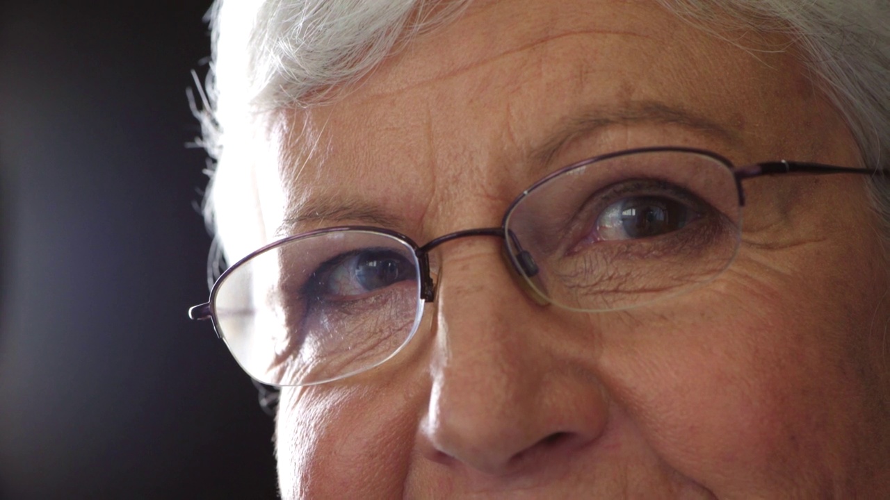 一位老妇人的肖像，对人性充满希望。用老花镜矫正视力的老奶奶特写。一张睿智女士的脸和眼睛，想着美好的回忆，做着白日梦视频素材