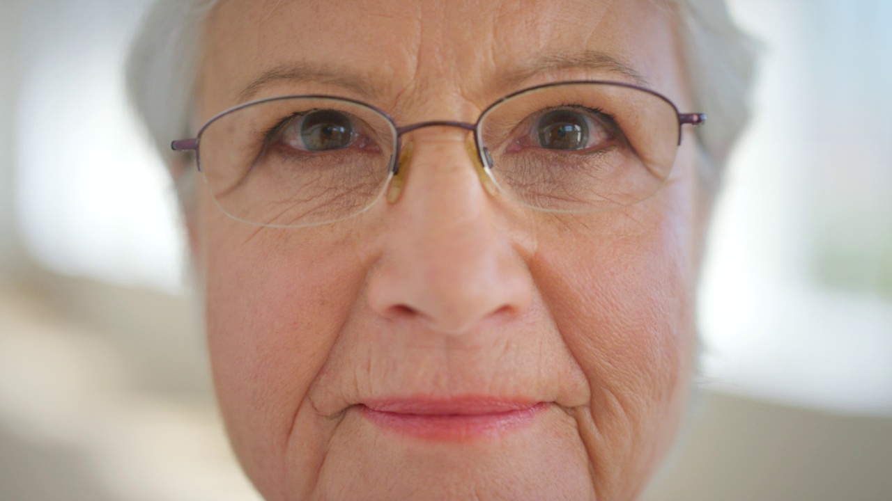 特写脸的高级妇女的眼睛与眼镜，以改善她的视力。肖像一位老妇人与眼镜帮助视力或近视。态度积极的年长女性视频素材