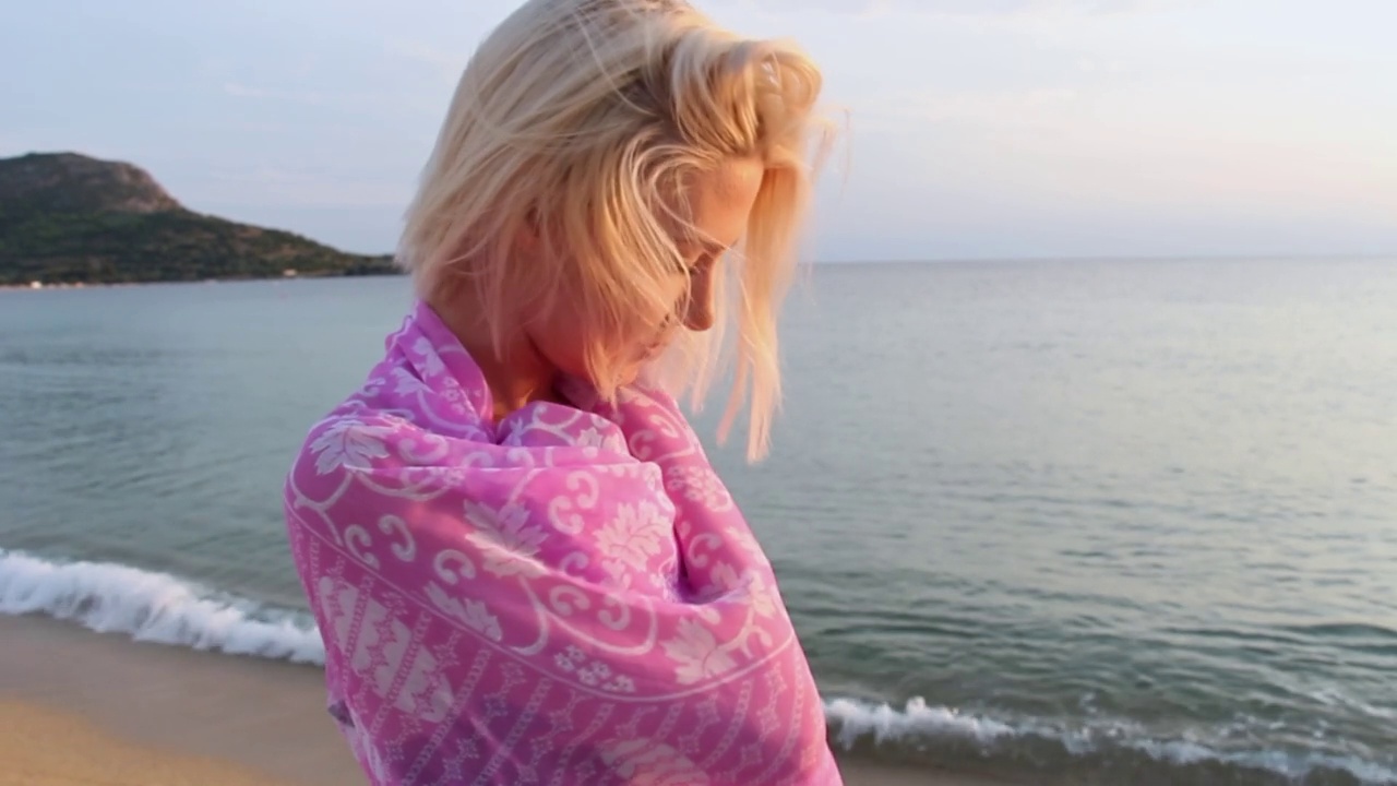 沙滩上戴着粉色围巾的年轻女子视频下载
