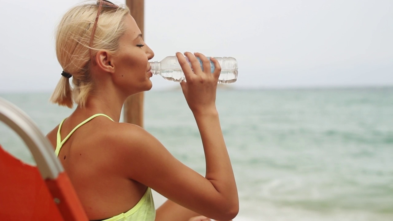 一个女人在海滩上喝水视频素材