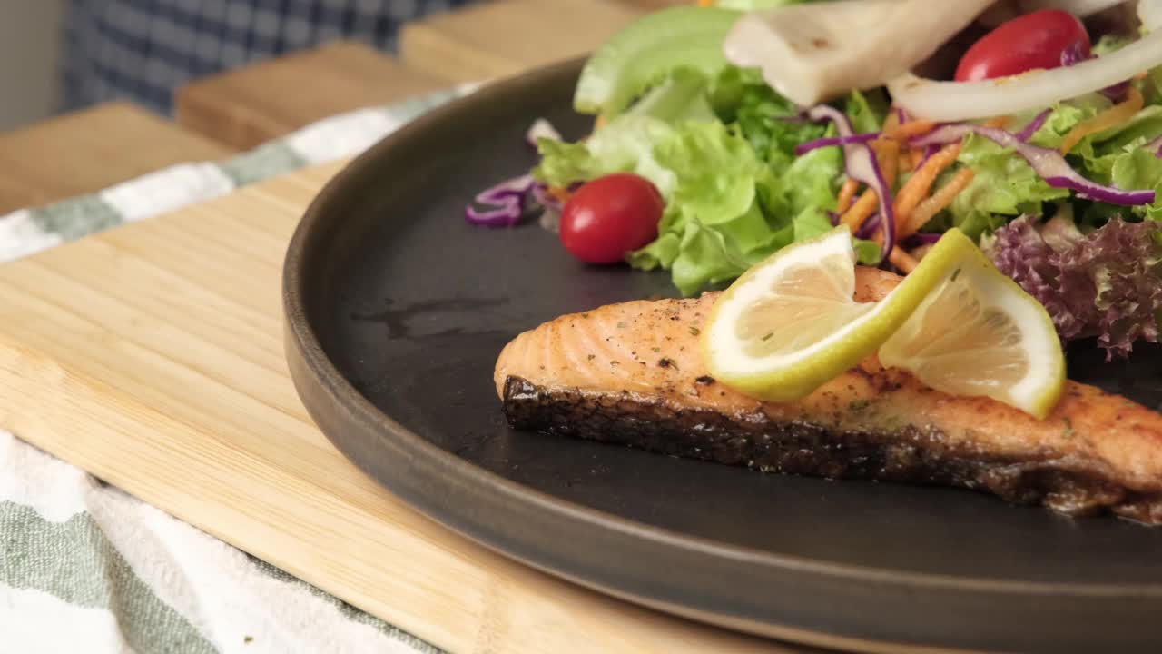 慢动作4k视频，用叉子吃烤鲑鱼蔬菜沙拉西红柿，蘑菇和绿色蔬菜。厨师将烤三文鱼做成一道菜，用柠檬片装饰。食物新鲜的食材。视频素材