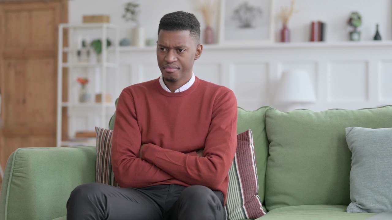 非洲男人坐在沙发上感到不安视频素材