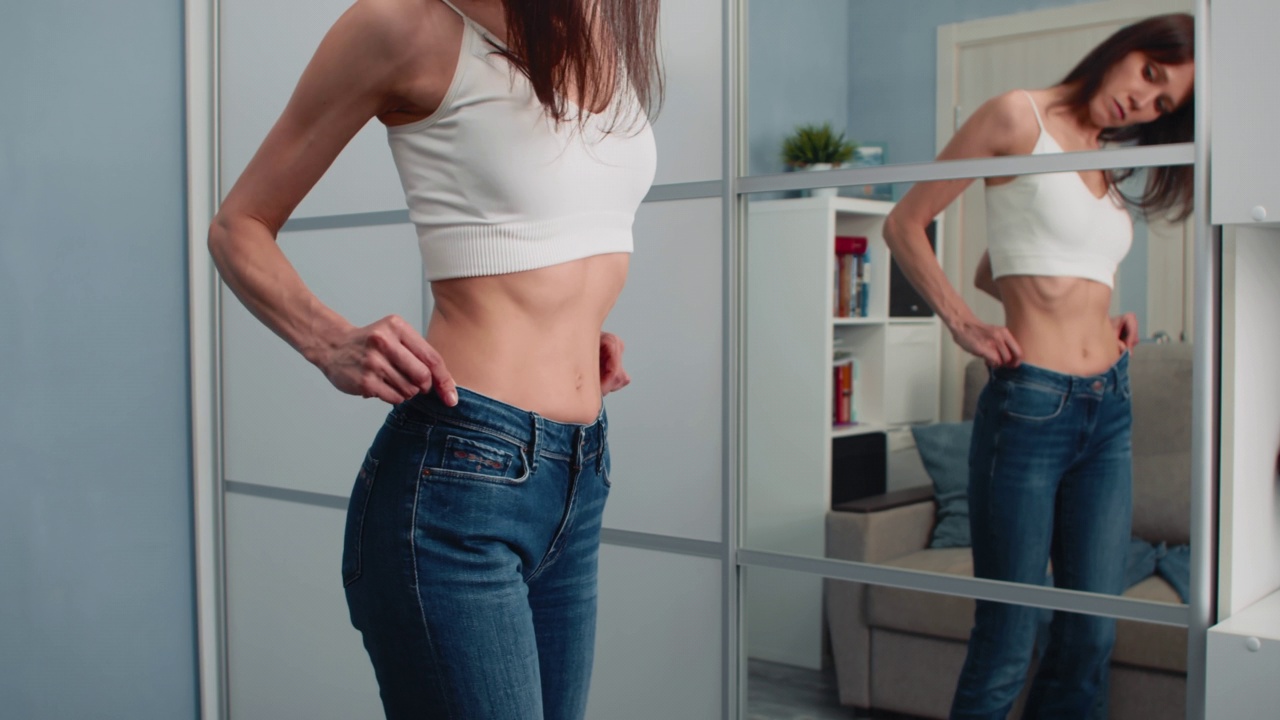 苗条的女人穿着太大的牛仔裤显示她是如何减肥的视频下载