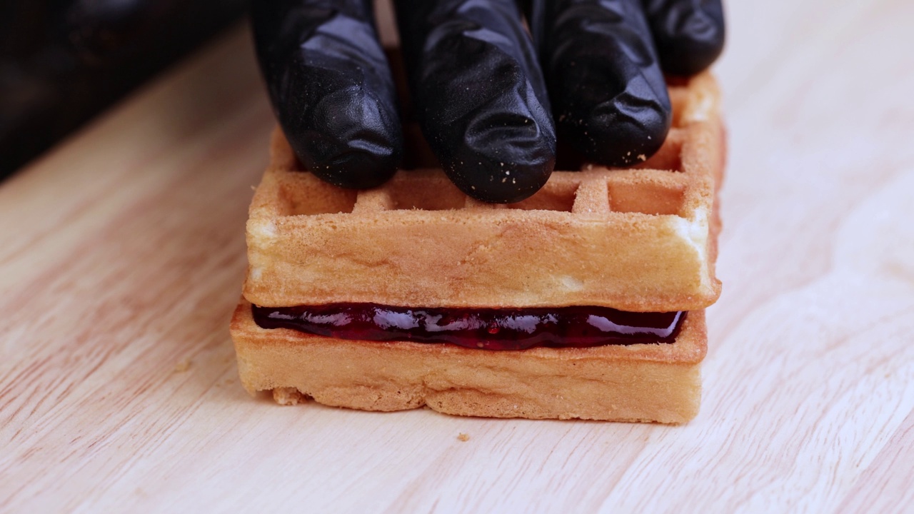 点击并制作一个由两片华夫饼和樱桃果酱组成的三明治视频素材