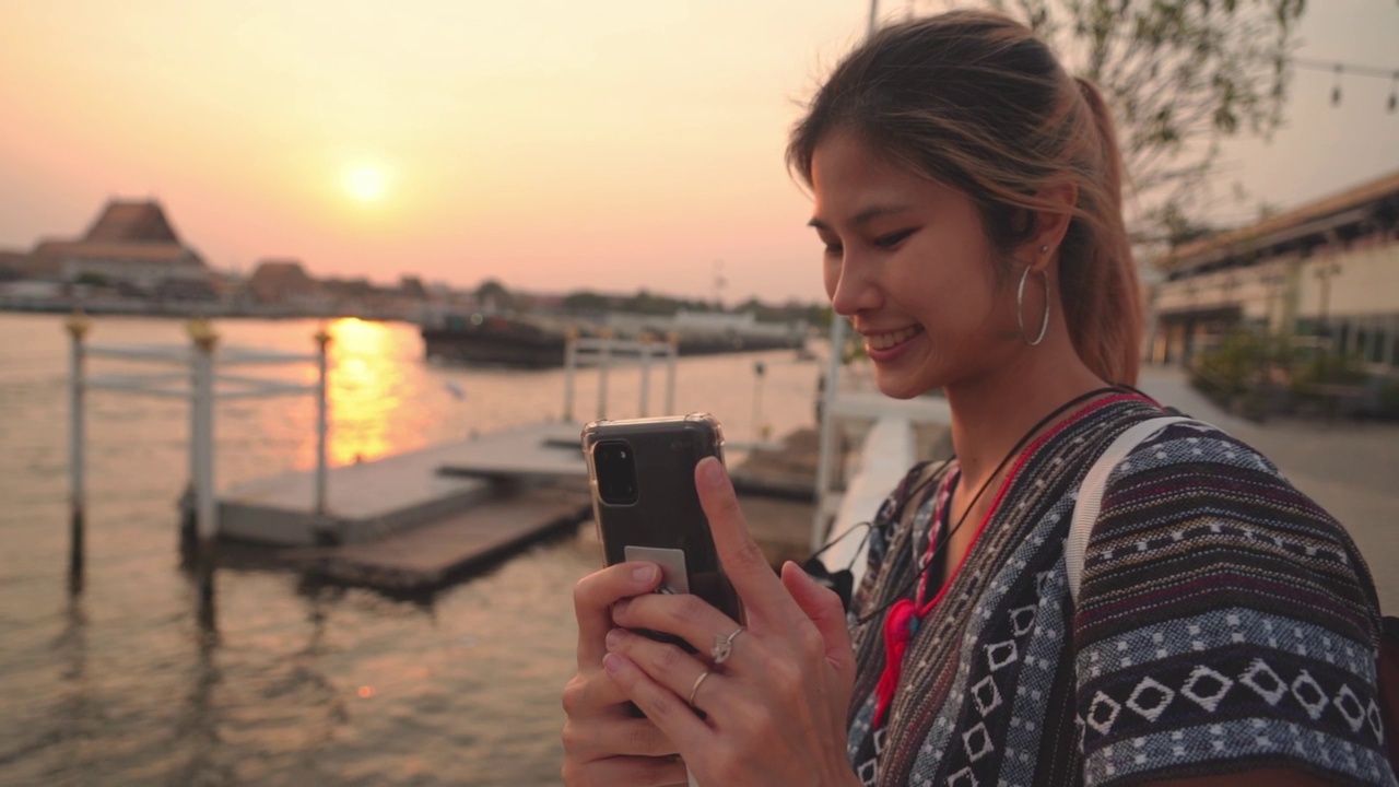 美丽的亚洲女游客正在以曼谷河为背景自拍视频素材
