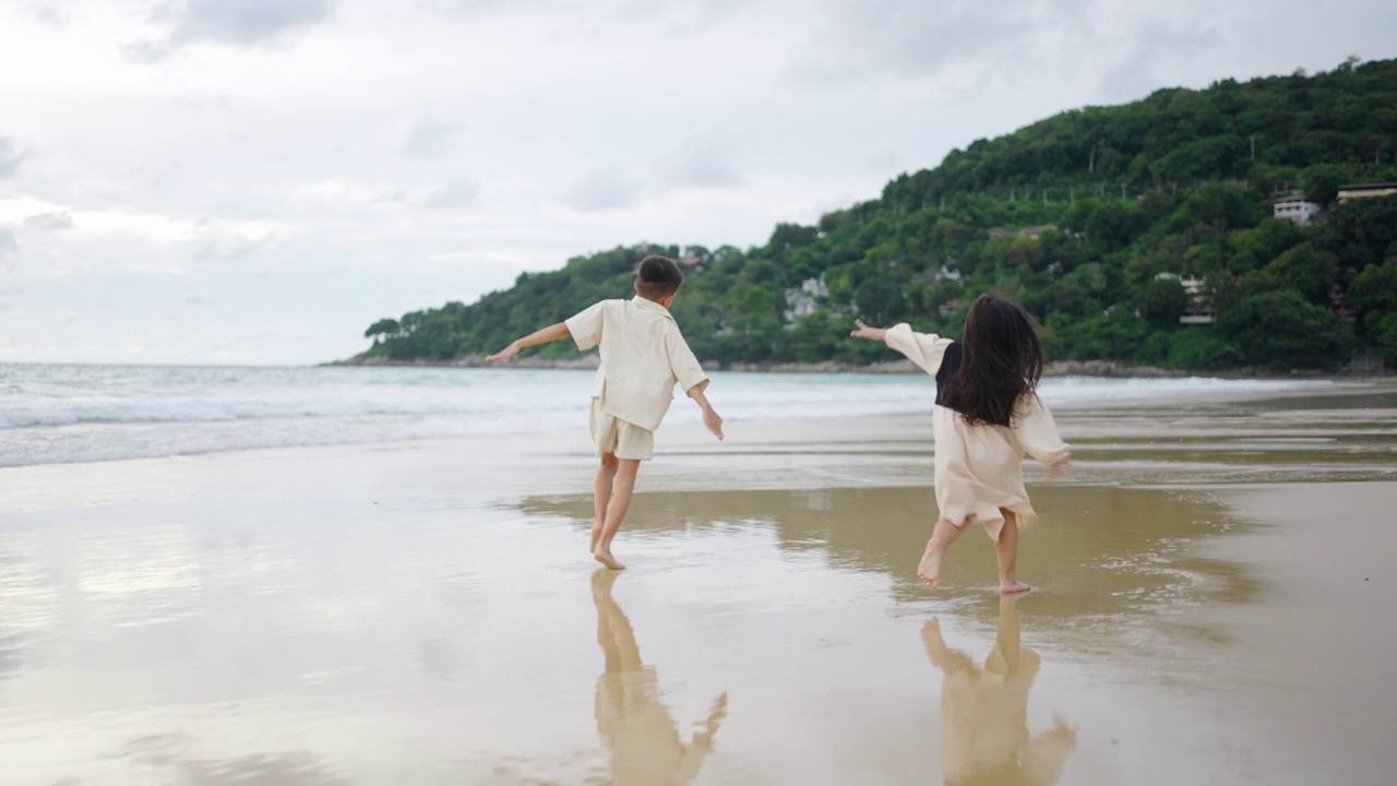 亚洲小男孩和女孩兄弟姐妹一起在夏天日落的海滩上玩耍。视频素材