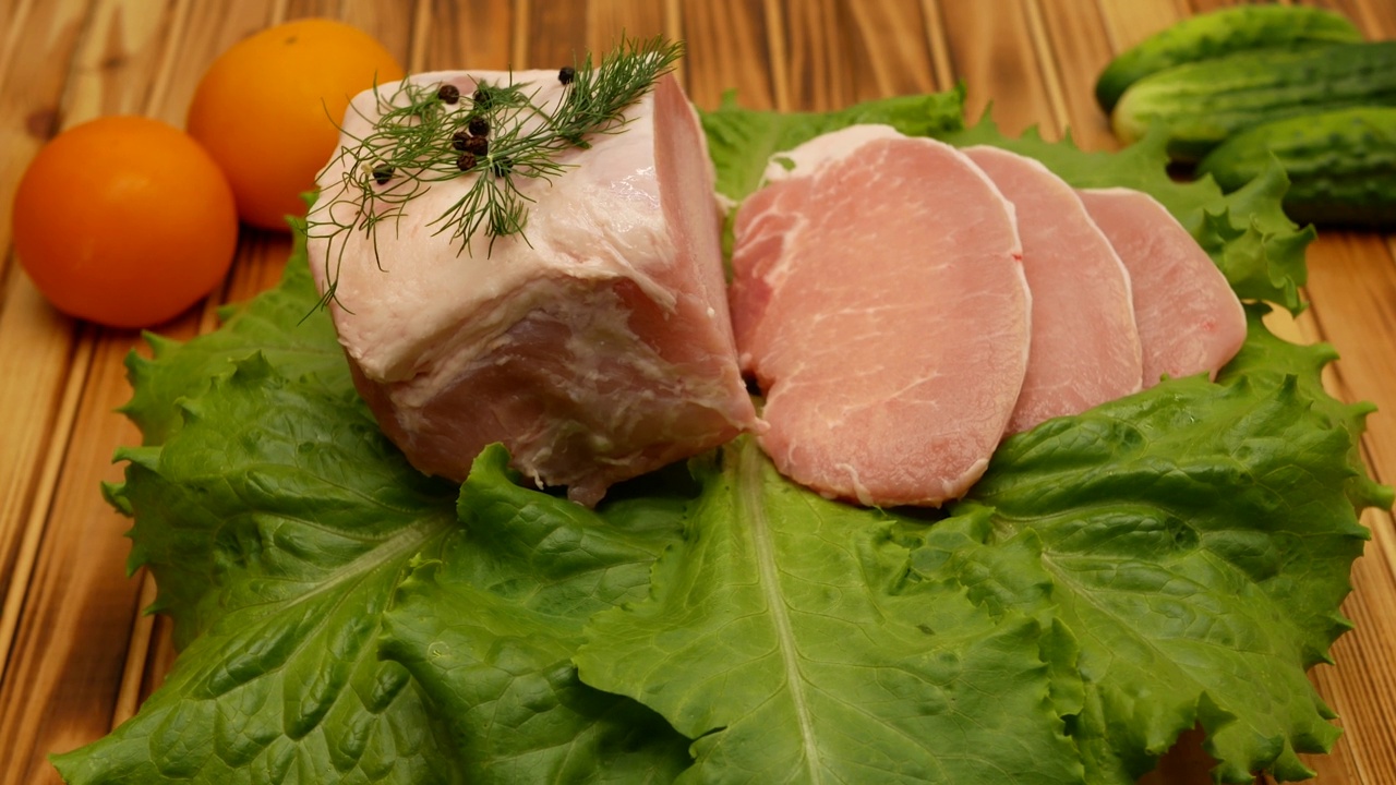 新鲜的生猪肉特写。准备煎。猪肉牛排。旋转。肉放在新鲜的绿色生菜叶子上。特写镜头视频素材