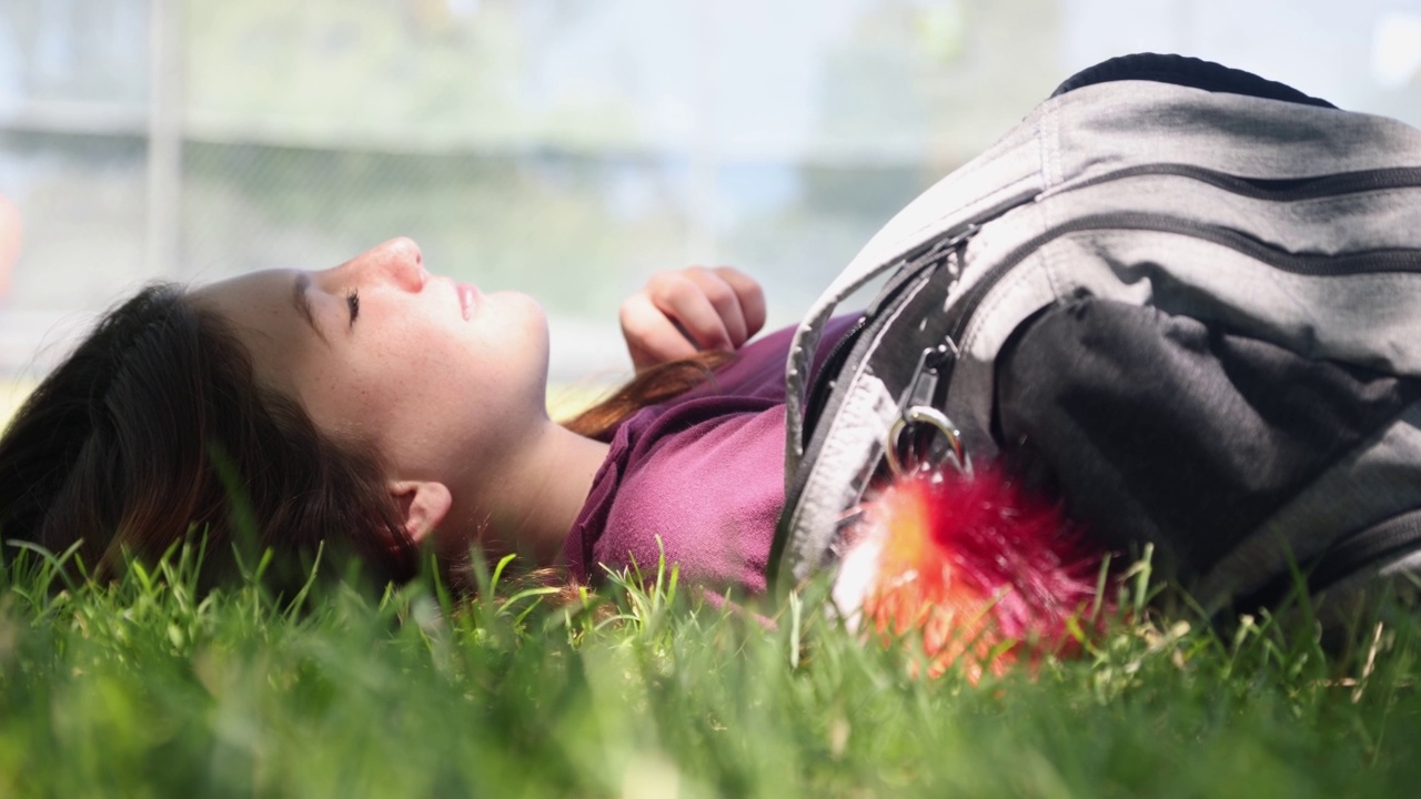 快乐的十几岁的女性放松，她躺在草地上视频下载