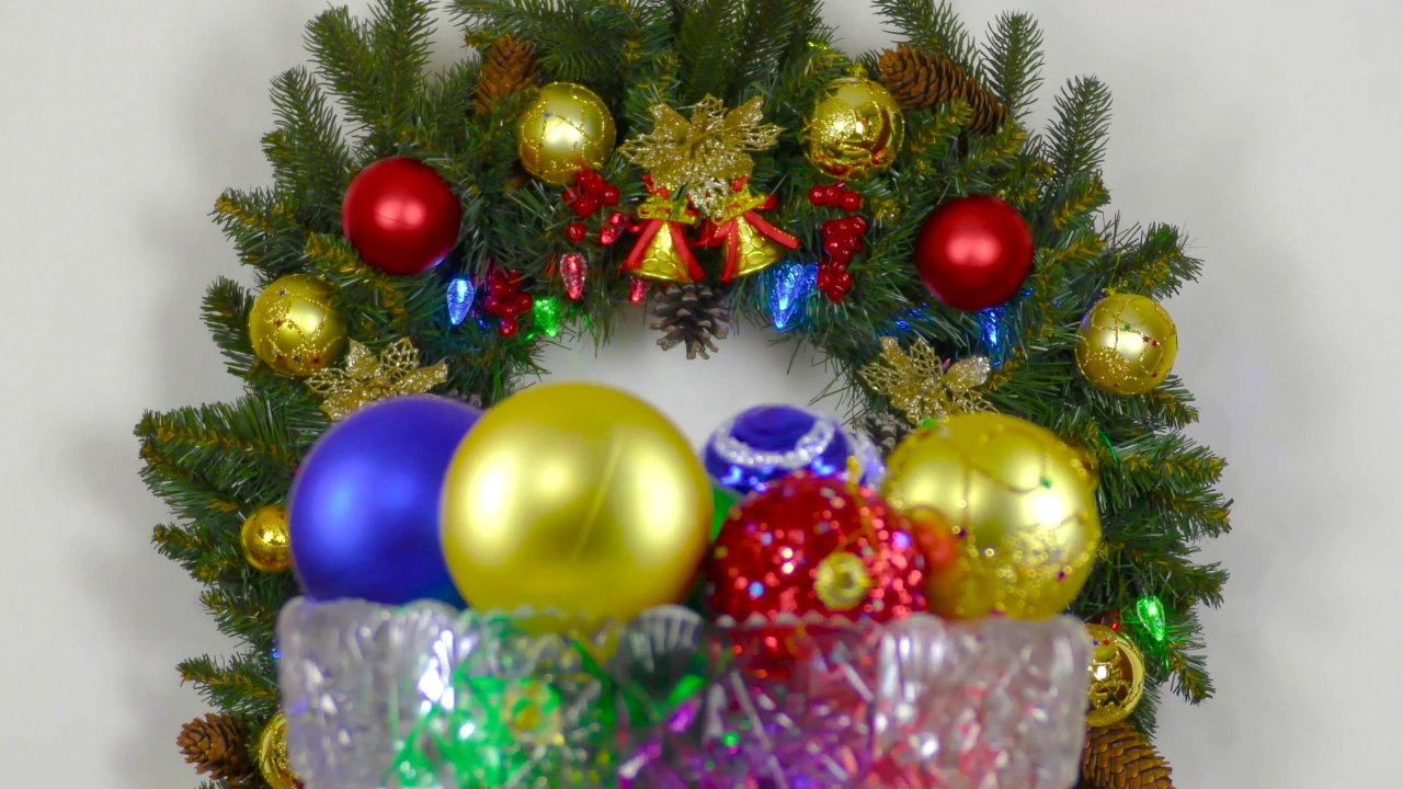 在圣诞花环的背景下，一个中间插着彩球的花瓶在旋转视频下载