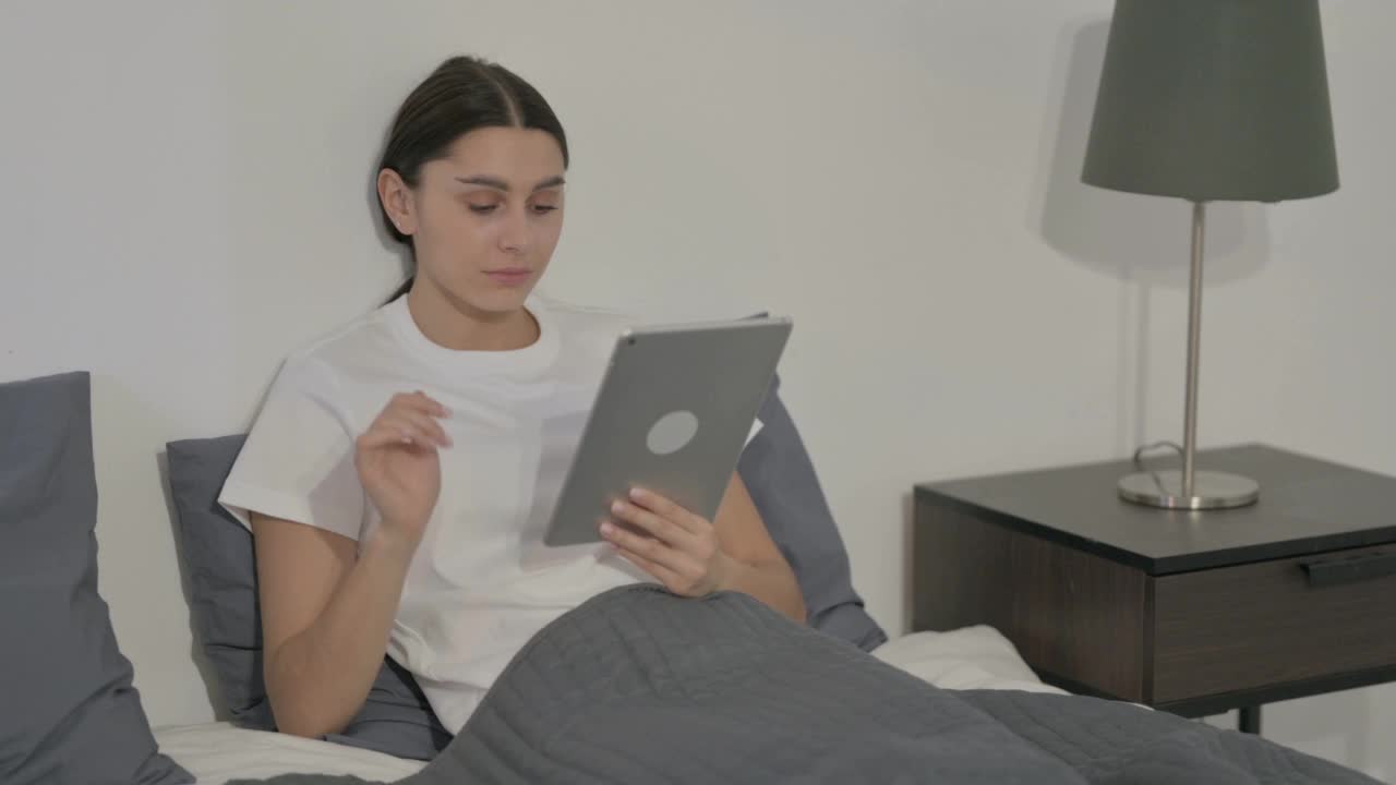 西班牙女性对在床上失去平板电脑的反应视频素材