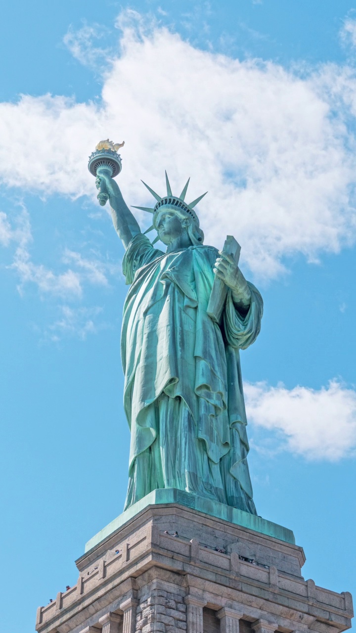 自由女神像纪念碑与时间推移的云在夏天的天空在纽约市，美国。美国旅游景点地标，美国旅游目的地，或国家象征概念视频素材
