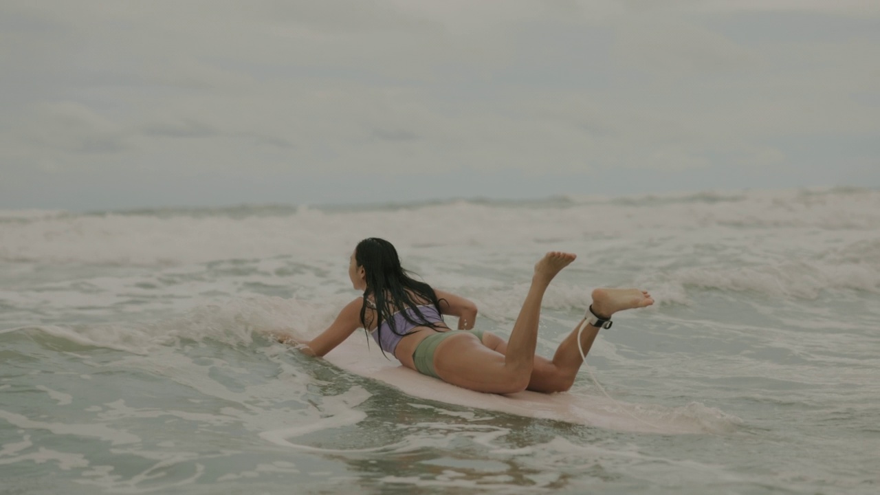 亚洲年轻女性冲浪桨冲浪板在海上。视频购买