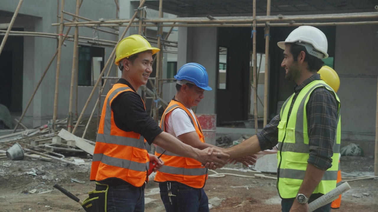 年轻的亚洲承包商团队和合作伙伴握手为团队合作成就，工程师和施工现场，建筑师握手为成功的协议和共同处理。视频素材