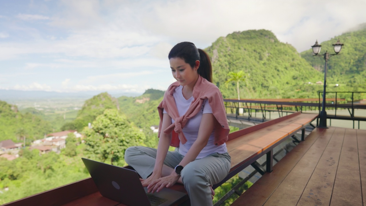 人像自由数字游牧民网页设计和开发微笑坐着使用笔记本电脑在咖啡馆旅行。女程序员编程远程工作在笔记本电脑制造被动进来。视频下载
