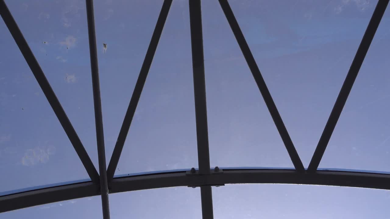 人行桥上空荡荡的长玻璃隧道。镜头在蓝天下的阳光下穿过玻璃隧道，最后是墙上的监控摄像头和“俄罗斯出口”的字样视频下载