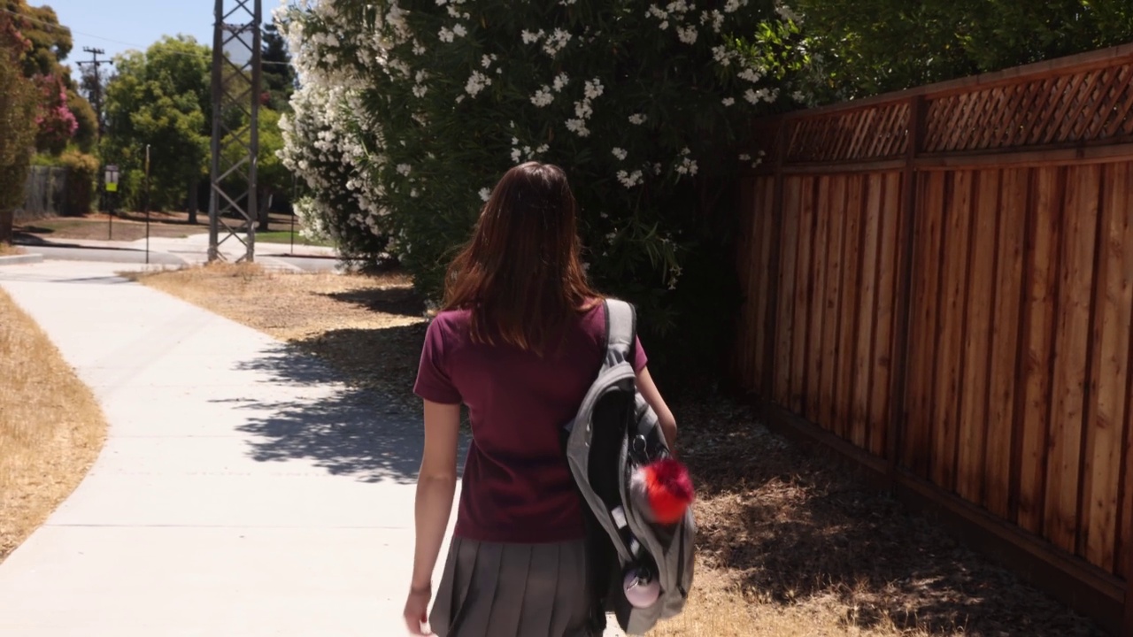 在一个阳光明媚的日子，女青少年步行去学校的后视图视频下载