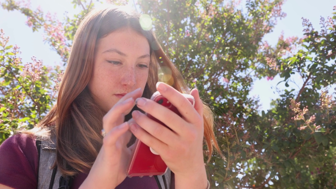 女青少年学生在上学途中使用社交媒体的特写视频下载