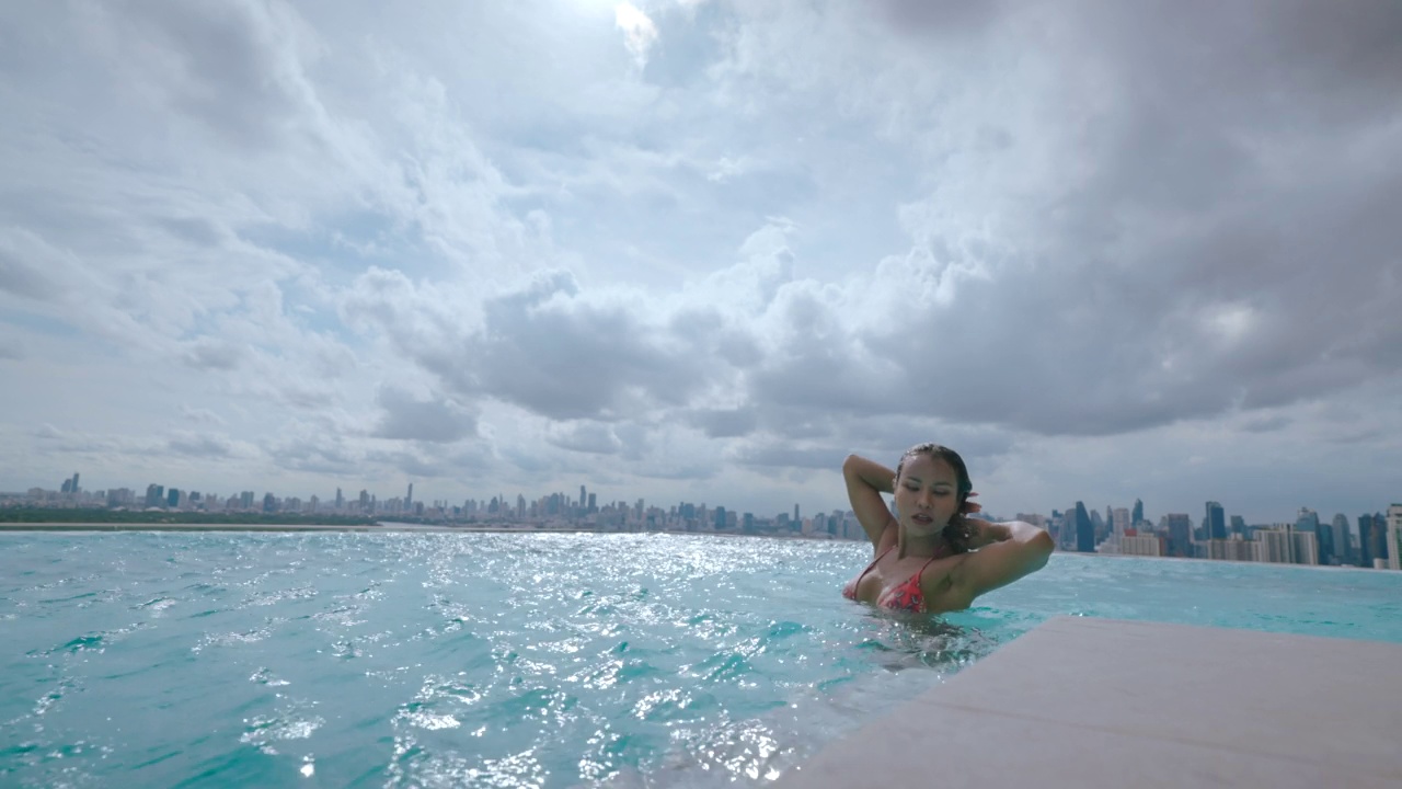 年轻的亚洲女性在户外游泳池放松快乐的时间。视频素材