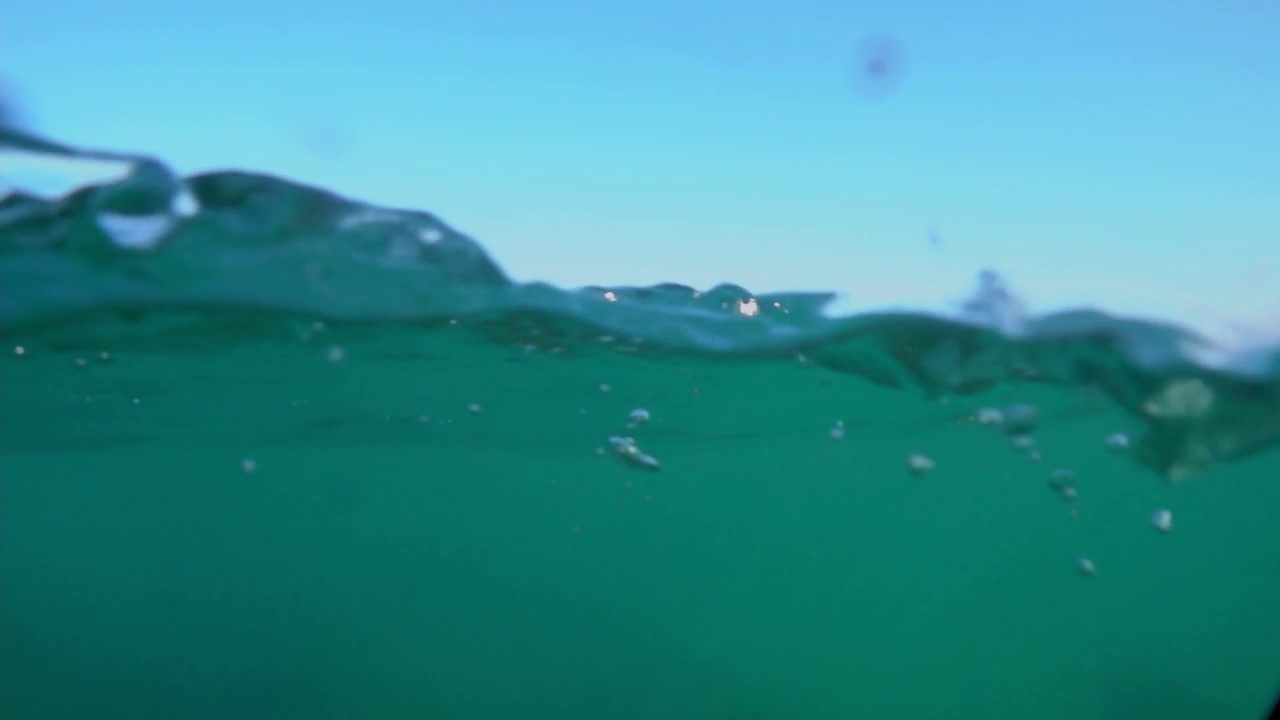 相机浸在水里，在快要淹死的大海上。美丽的光线折射在水面的波浪，潜水，浮潜。视频素材