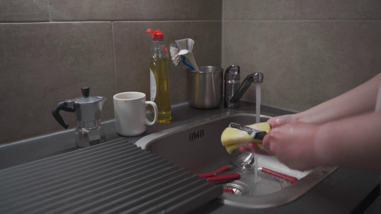 特写一名女性在家里的厨房手洗厨房水槽用具，并使用清洗液。主题是家政和家务。打扫房子，做家务。做家务视频素材
