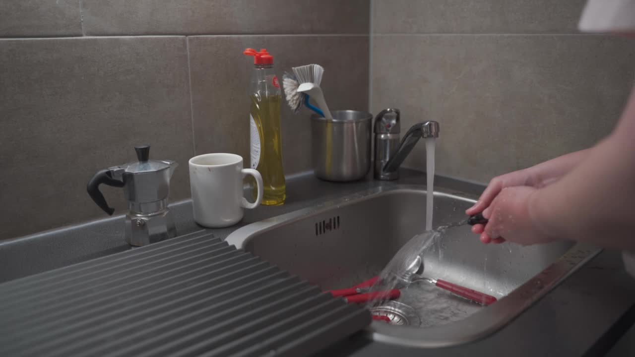 特写一名女性在家里的厨房手洗厨房水槽用具，并使用清洗液。主题是家政和家务。打扫房子，做家务。做家务视频素材
