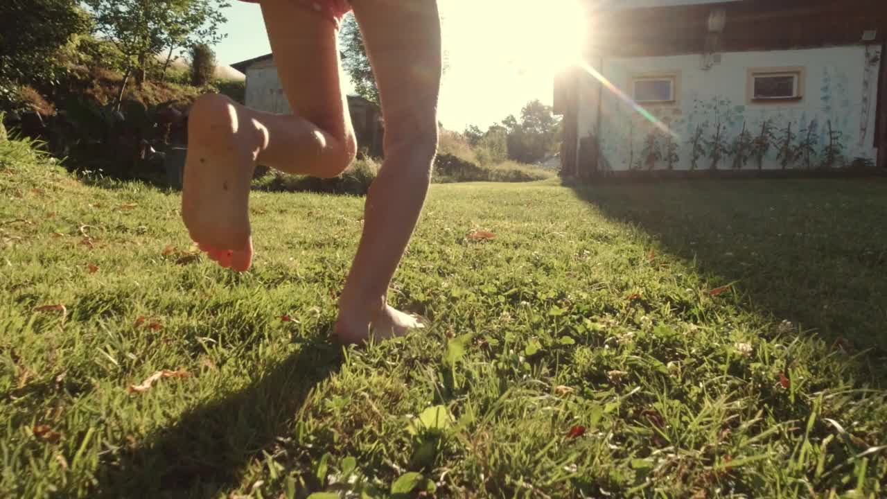 年轻女孩赤脚跑在农场草地上日落慢动作视频下载