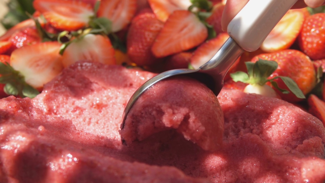 手拿着特制的冰淇淋勺正在舀新鲜的草莓冰淇淋视频下载