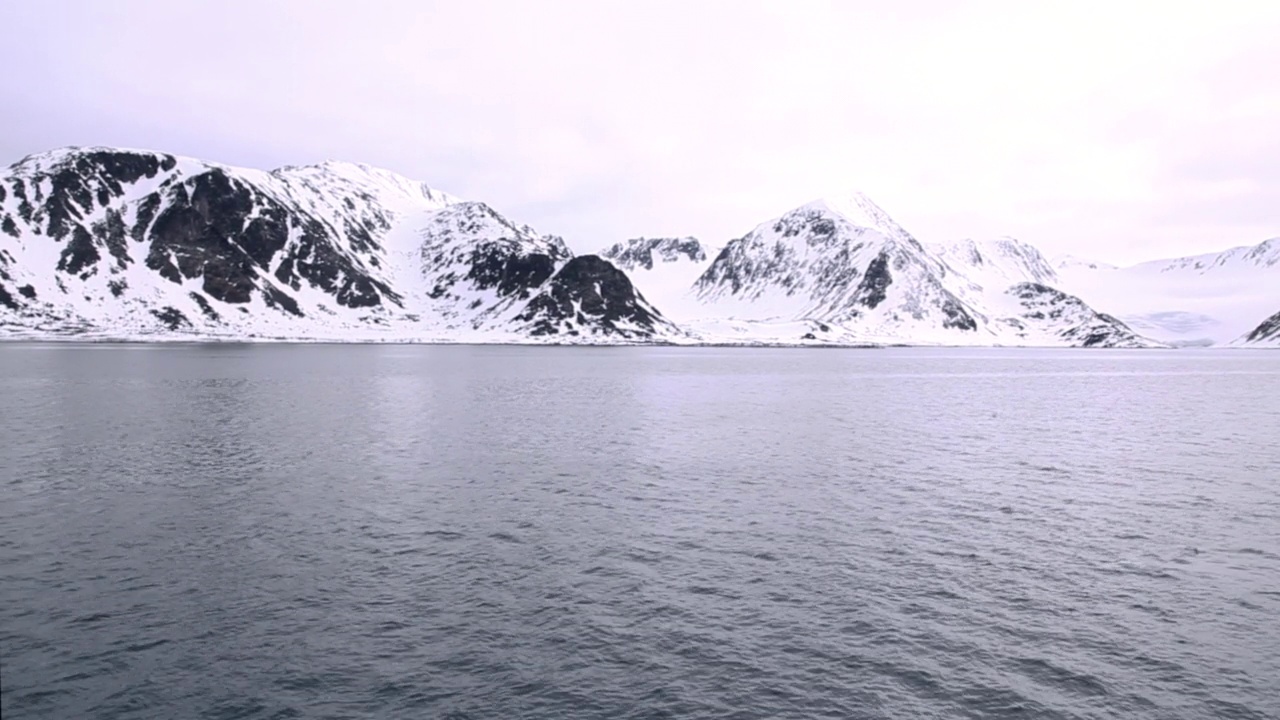 挪威斯瓦尔巴群岛，斯匹次卑尔根群岛，风平浪静的海边的雪山视频下载