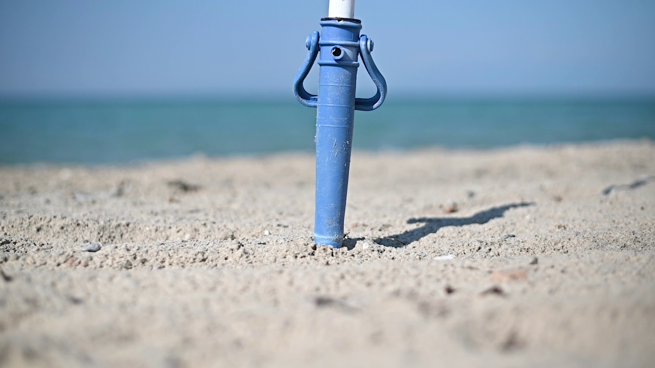 在沙滩上搭建遮阳伞架。缓慢的运动。海滩活动视频素材