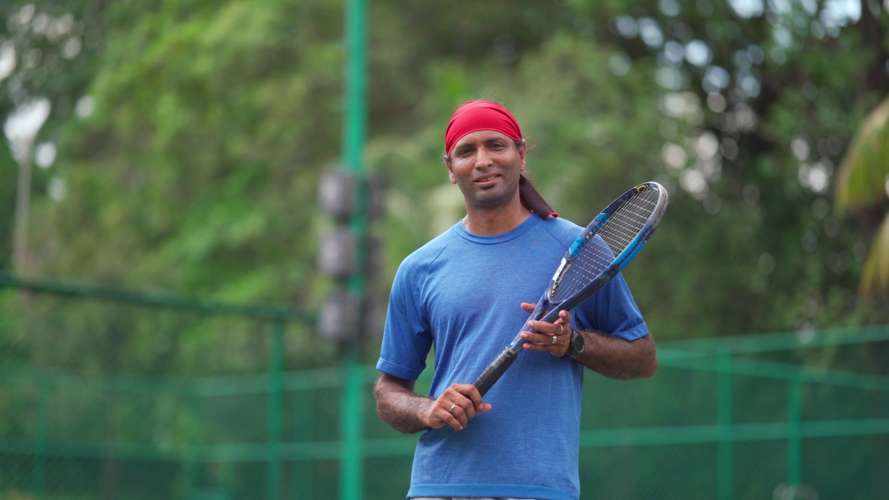 亚洲印度男性网球运动员的肖像拿着球拍看着相机视频下载