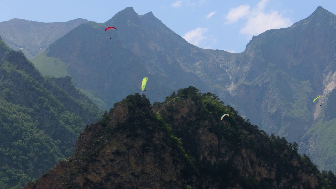 滑翔伞飞行员驾驶滑翔伞在云和青山之间飞行。视频素材