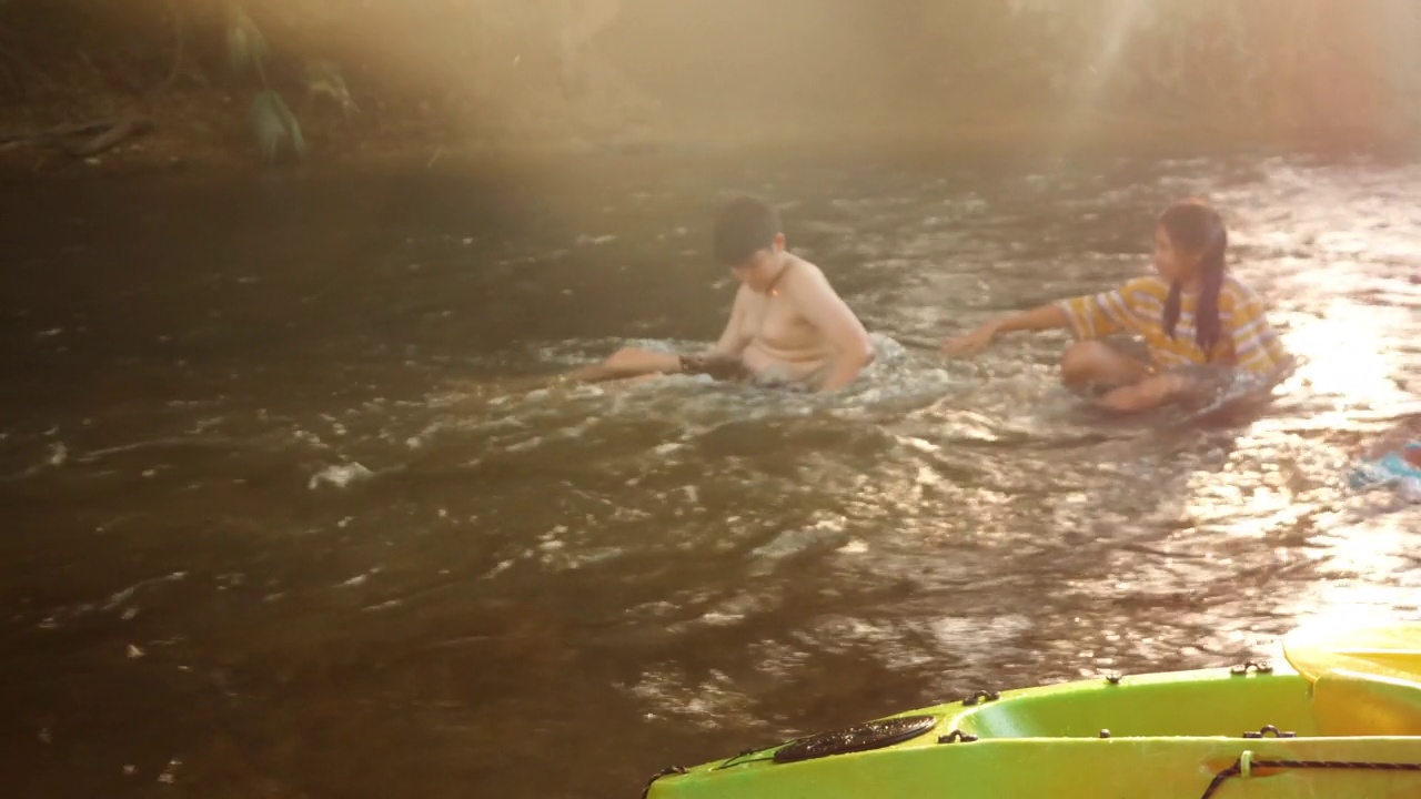 快乐的亚洲孩子们一起在阳光下的河流中放松，户外生活理念。视频素材