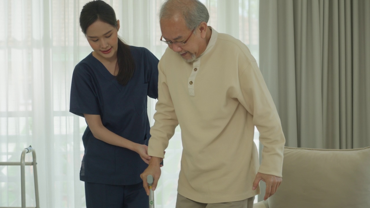 家庭保健东南亚老年人。护理护士或理疗师帮助残疾的老年病人在护理中行走视频下载