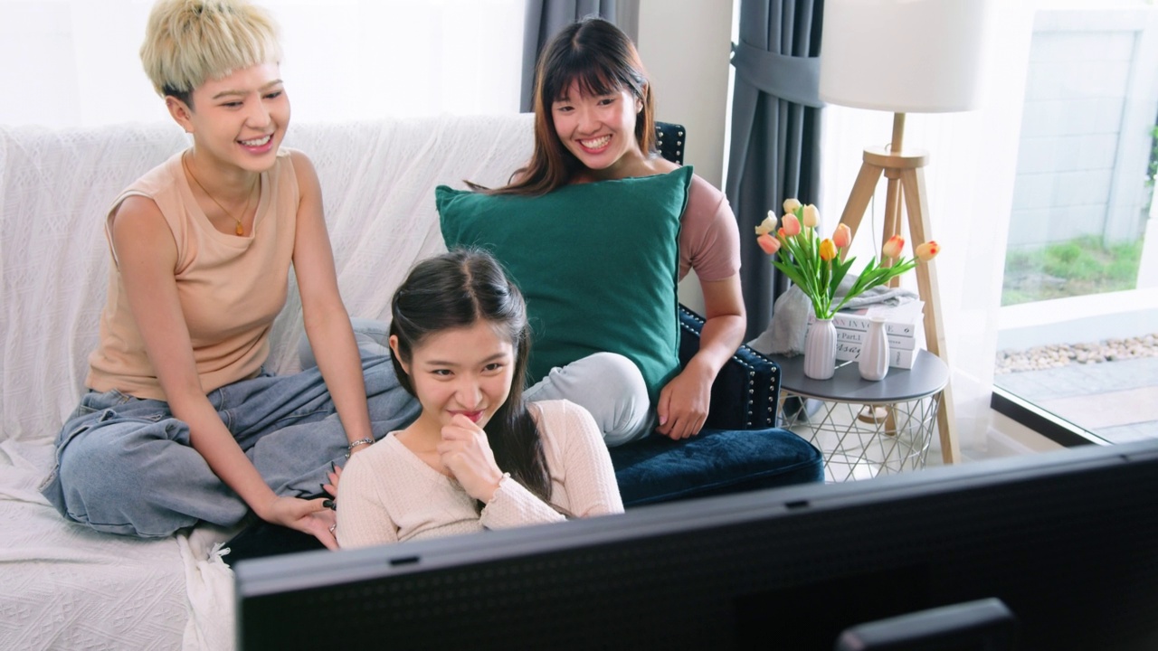 三个女性朋友在家里的客厅里看电影。视频下载