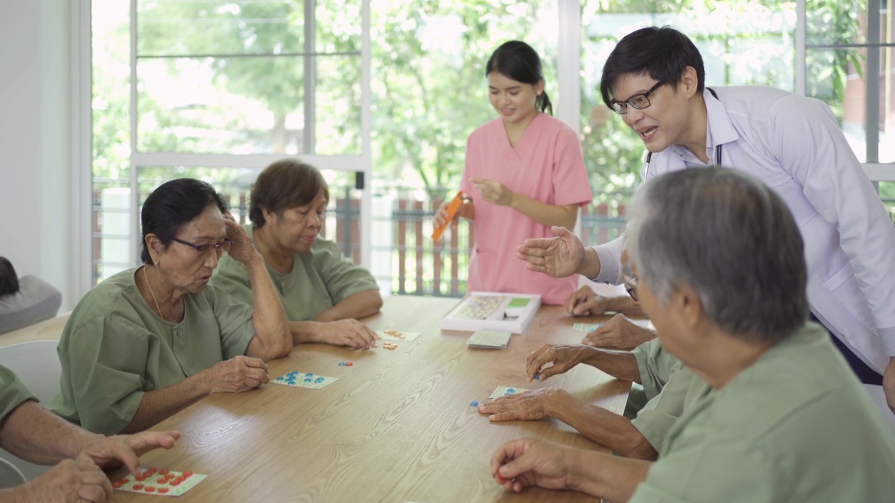 一群快乐的亚洲老人或退休老人与护士和医生在疗养院玩游戏的肖像。老年人生活方式活动娱乐。退休社区。卫生保健视频素材